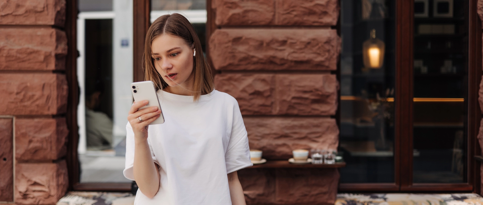Tânără privind ecranul telefonului mobil, imagine sugestivă pentru utilizarea excesivă a telefonului și impactul asupra emoțiilor și atenției